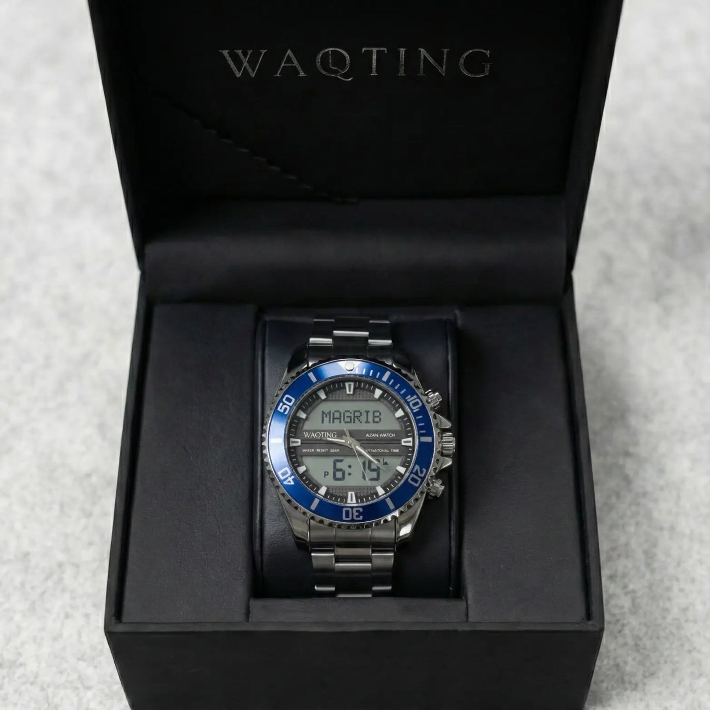 Silver watch with blue accents in a black box, featuring the brand 'WAQTING'.