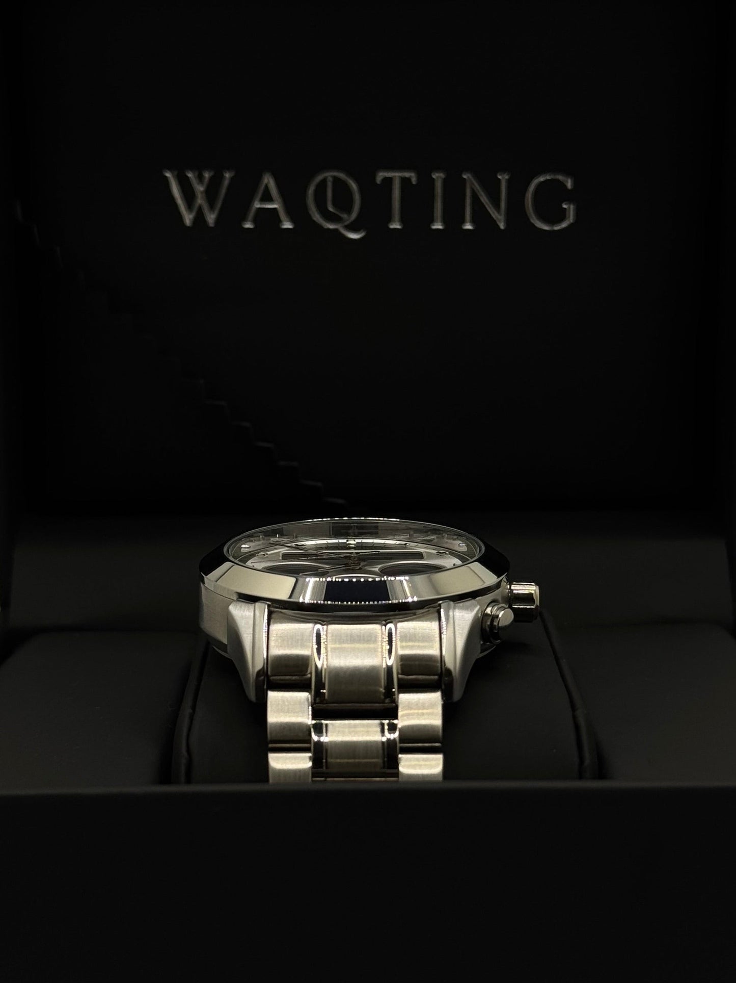Silver watch on a black background with 'WAQTING' branding.